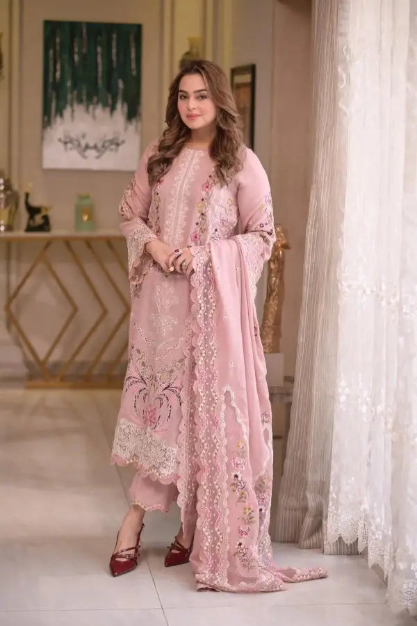 Woman in a pink embroidered outfit standing in a decorated room.