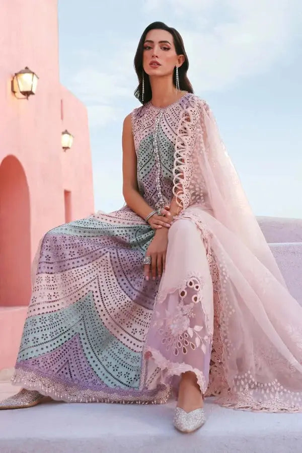 Woman in a colorful traditional outfit sitting on a pink building with a blue sky.