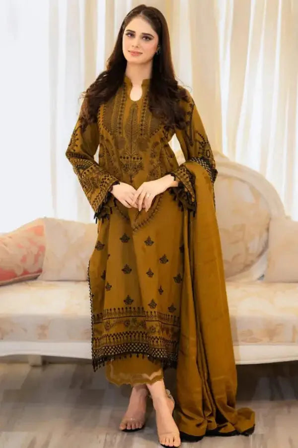 Woman wearing a mustard yellow traditional outfit with black patterns in a well-lit room.