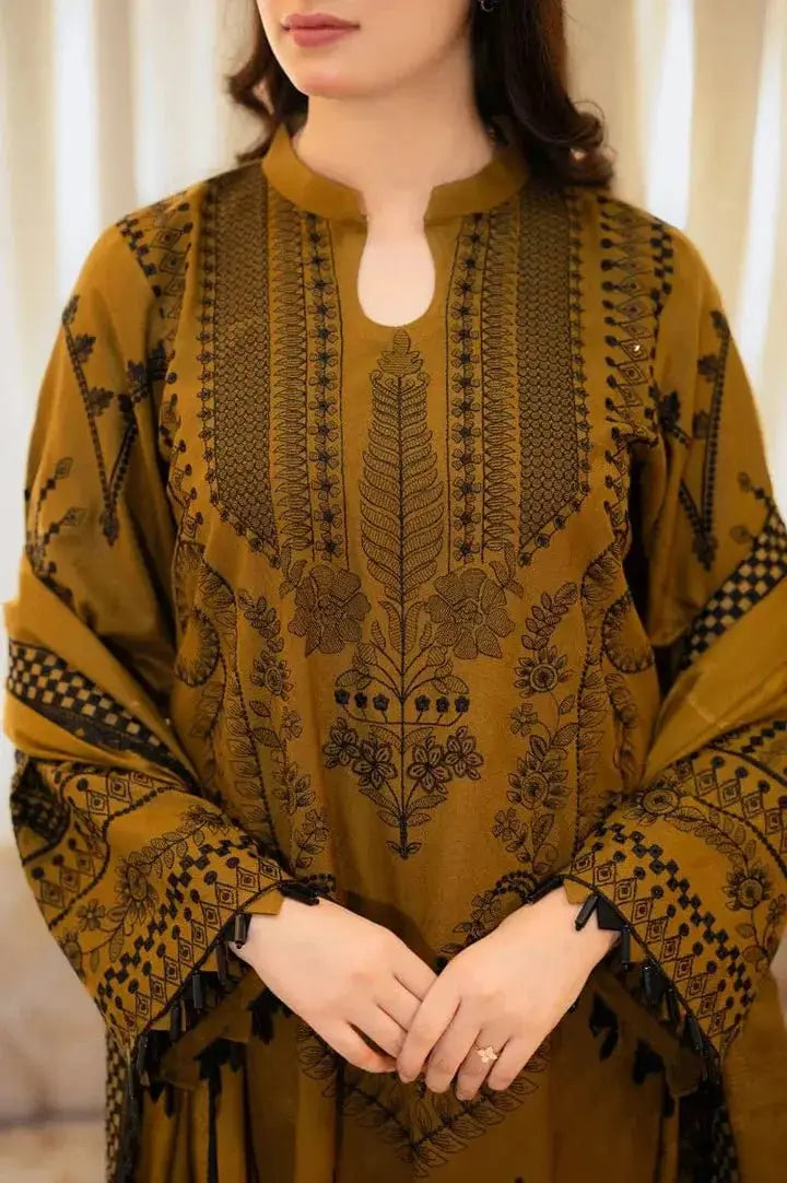 Woman wearing a mustard yellow embroidered traditional outfit with black patterns.